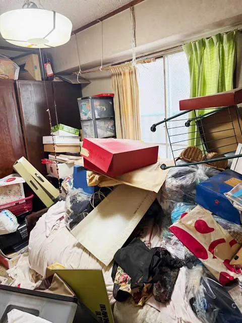 家具や箱、衣類などが置かれた片付け前の和室