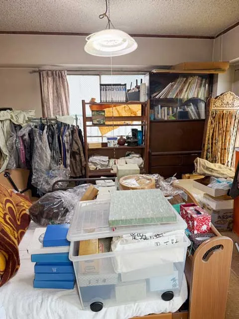 衣類や収納用品が置かれた片付け前の洋室